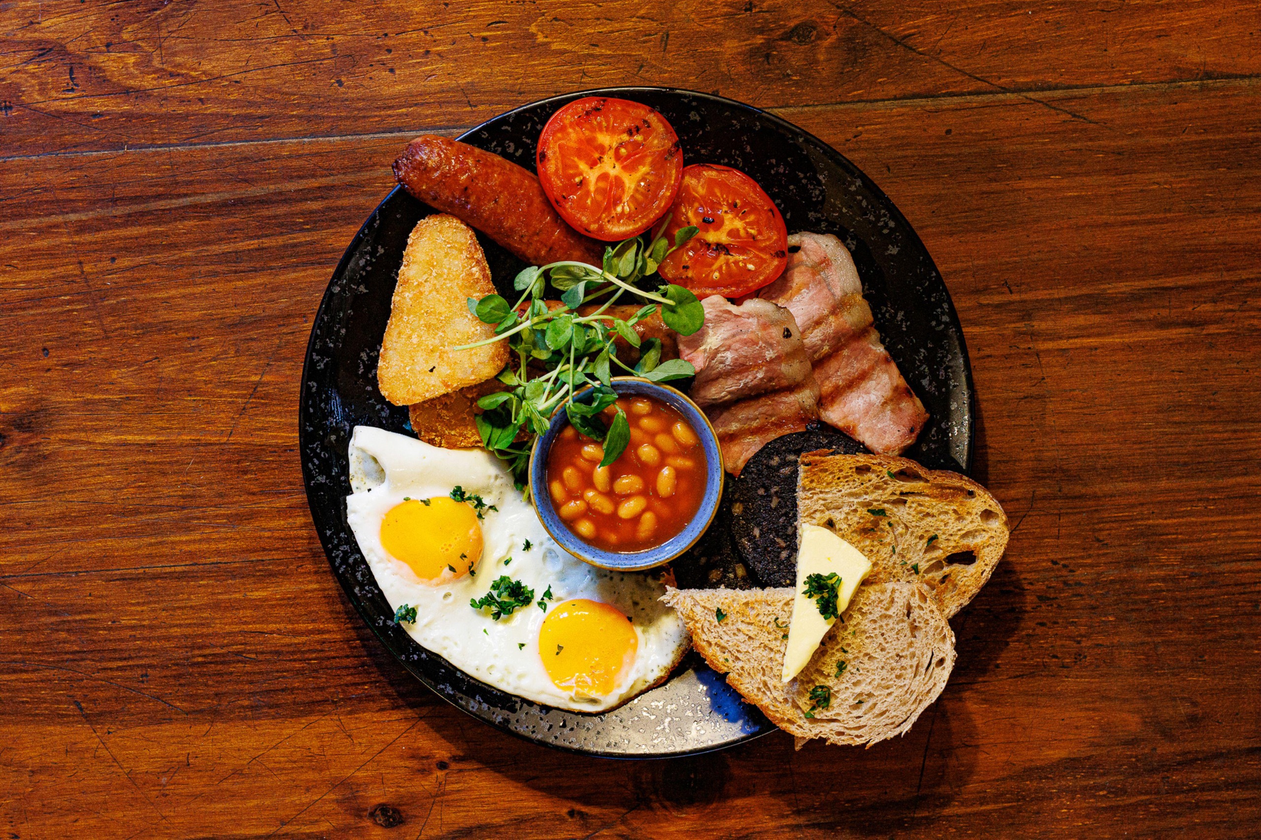 A full-english breakfast, viewed from above on a wooden table