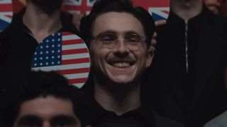 Timothee Chalamet smiling holding a table tennis paddle with an American flag on it in Marty Supreme