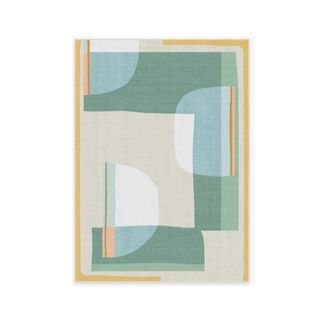 A geometric patterned outdoor rug with white, blue, and green shapes, a beige base, and a gold border