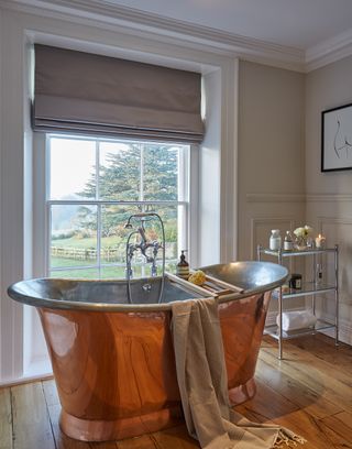 Bathroom with a copper bath and a fabric black out blind