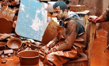 A Hungarian man rests in his garden after trying to rescue his belongings from the toxic sludge that has killed four people and inundated three villages.