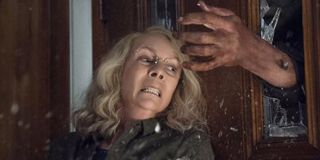 Jamie Lee Curtis Laurie Strode blocking a door Michael Myers reaching in 2018 Halloween