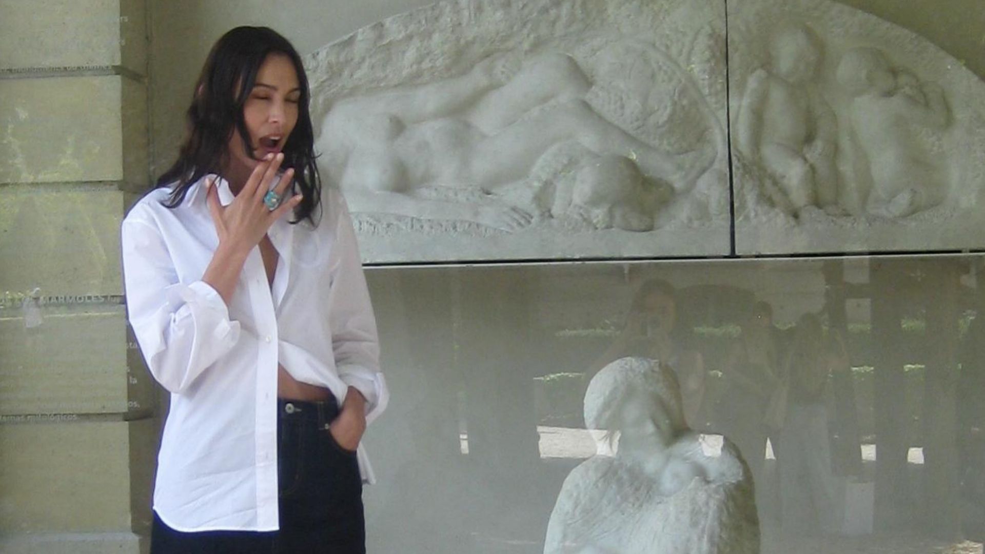 Alexa Chung wears a black denim miniskirt with silver bow heels and a white cotton button-down shirt.