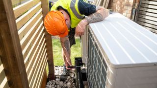 An air source heat pump being installed on the side of a house