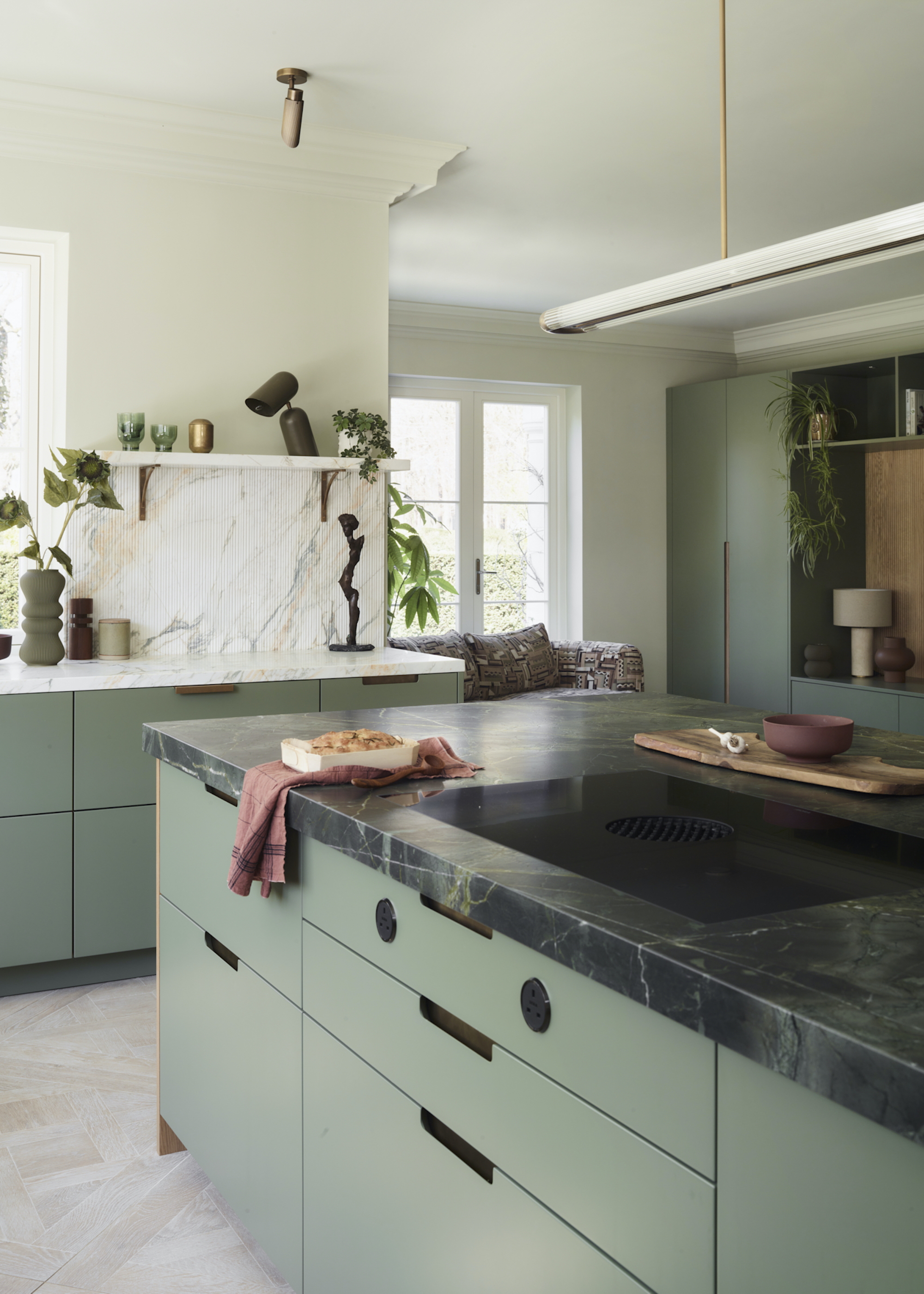 green kitchen with green quartzite tops on the island and the rest of the kitchen counters. Above the Kitchen island is a large pendant light