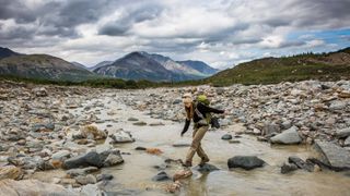 Hiker using large stepping stones to cross a river