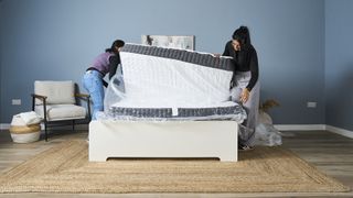 Two members of the Tom's Guide sleep team unwrap the Emma Elite Mattress and install it on a bedframe