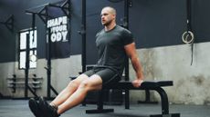 A man performing tricep dips on an exercise bench