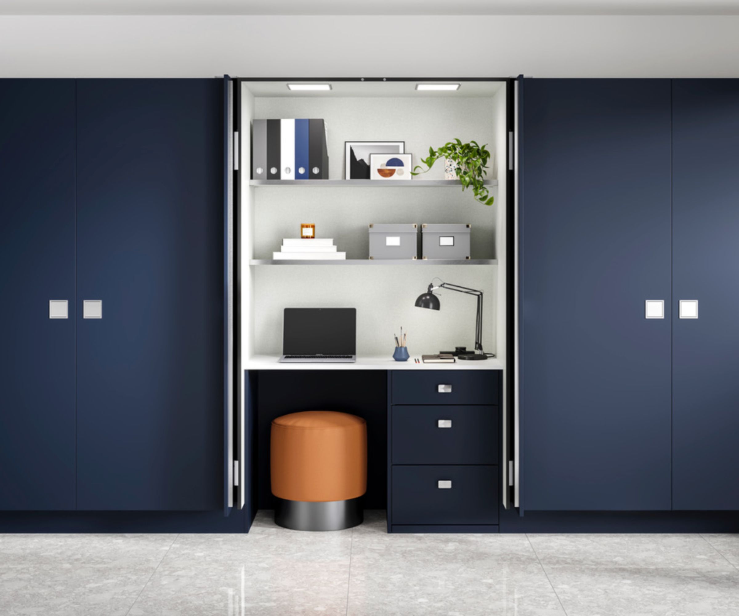 Sleek hidden home office with navy blue built-in cupboards, a compact white desk, floating shelves, and an orange stool tucked neatly underneath.