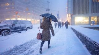 Woman struggles to walk through windy snowstorm.