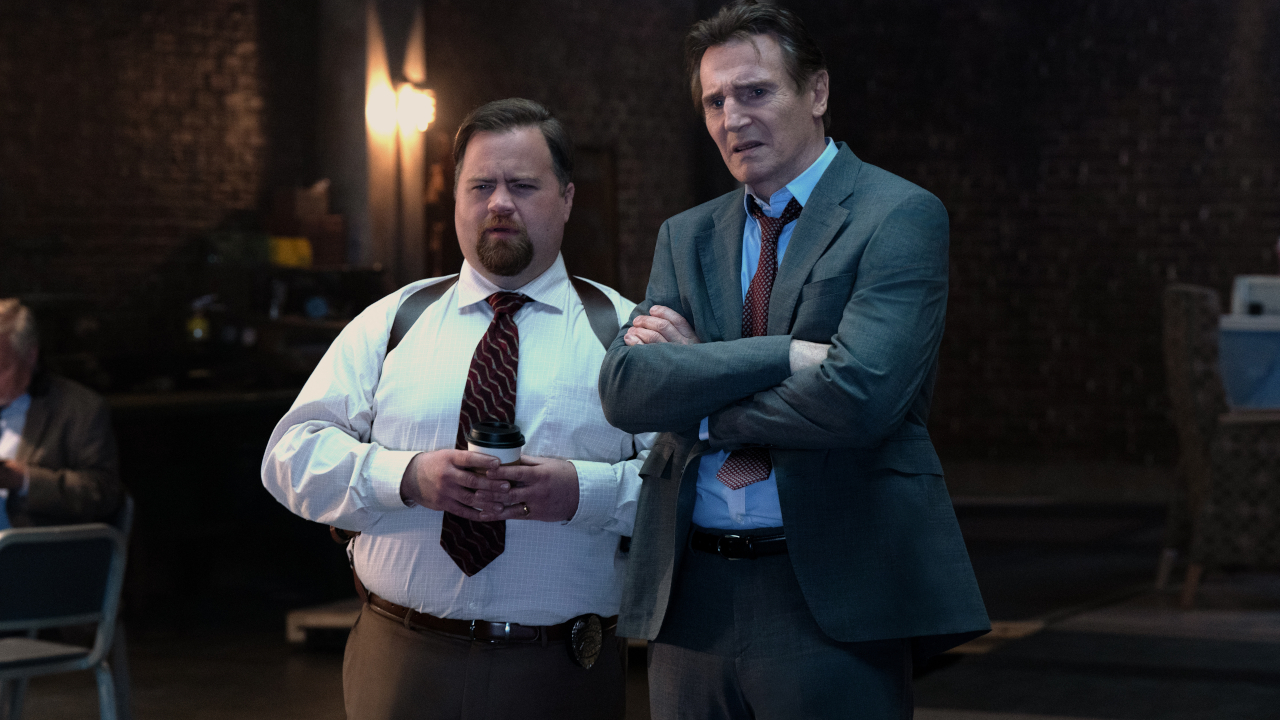 Paul Walter Hauser and Liam Neeson stand together looking puzzled in The Naked Gun.