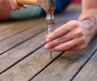 Using a nail punch to fix a wooden deck