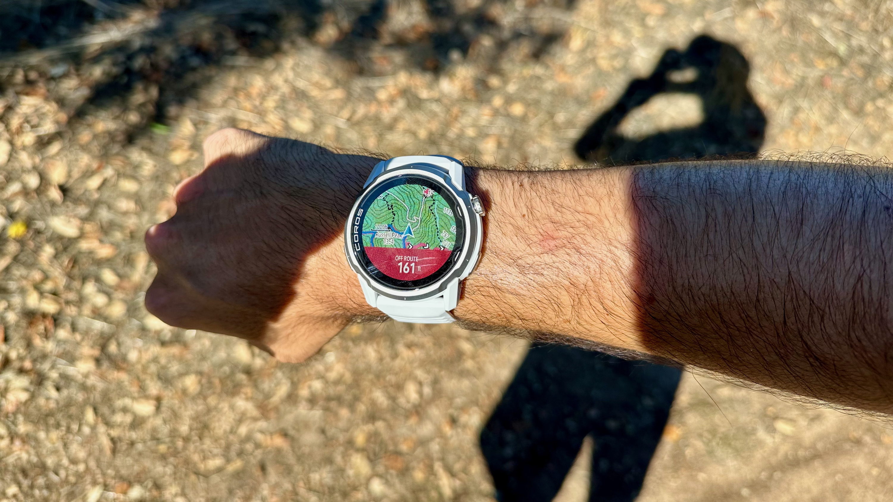 A photo of the COROS APEX 4 on the author's wrist showing a topographic map with turn-by-turn navigation and a red "Off route" pop-up.