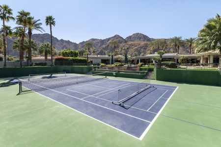 View of a full size tennis/pickleball court with mountain backdrop at a luxury, upscale estate in Indian Wells, California.