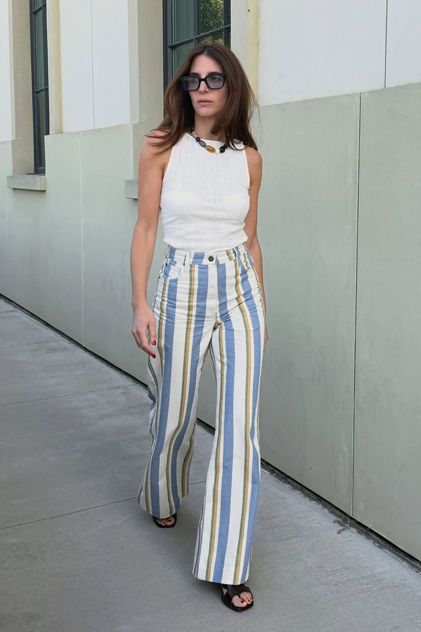 a woman wearing a white ribbed tank top and striped blue and white jeans