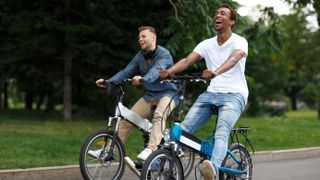 Two young men riding e-bikes in a park
