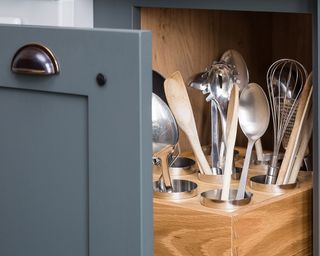 A close up shot of a grey pull-out drawer storing organised utensils