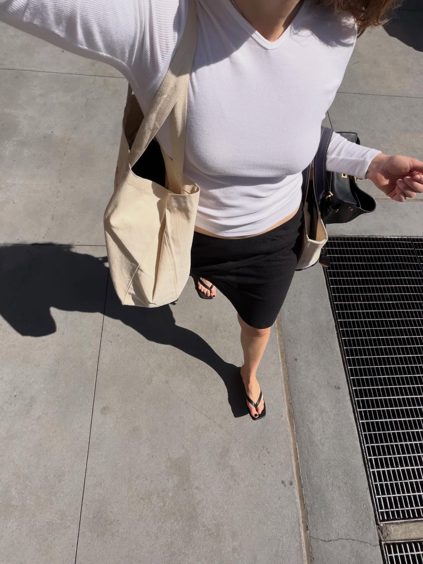 Who What Wear editor wearing a knee-length skirt and flip-flops.