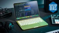 An Apple MacBook Neo on a studio desk with MIDI controller, audio interface, studio monitors, and studio headphones. The MusicRadar deals logo is in the top right corner.