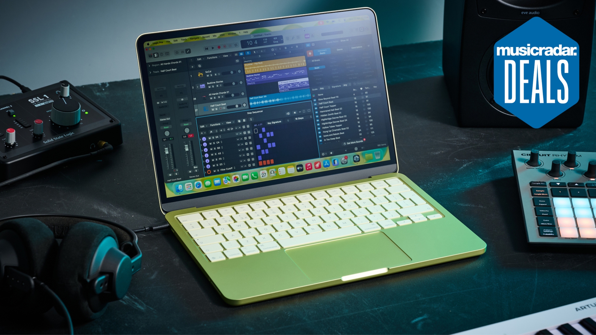 An Apple MacBook Neo on a studio desk with MIDI controller, audio interface, studio monitors, and studio headphones. The MusicRadar deals logo is in the top right corner.
