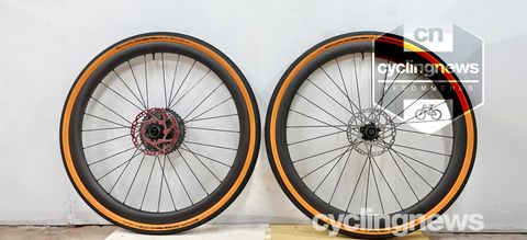 A pair of VeloElite Carbon 350 Gravel disc wheels leaning against a white wall, with a 'recommends' badge overlaid