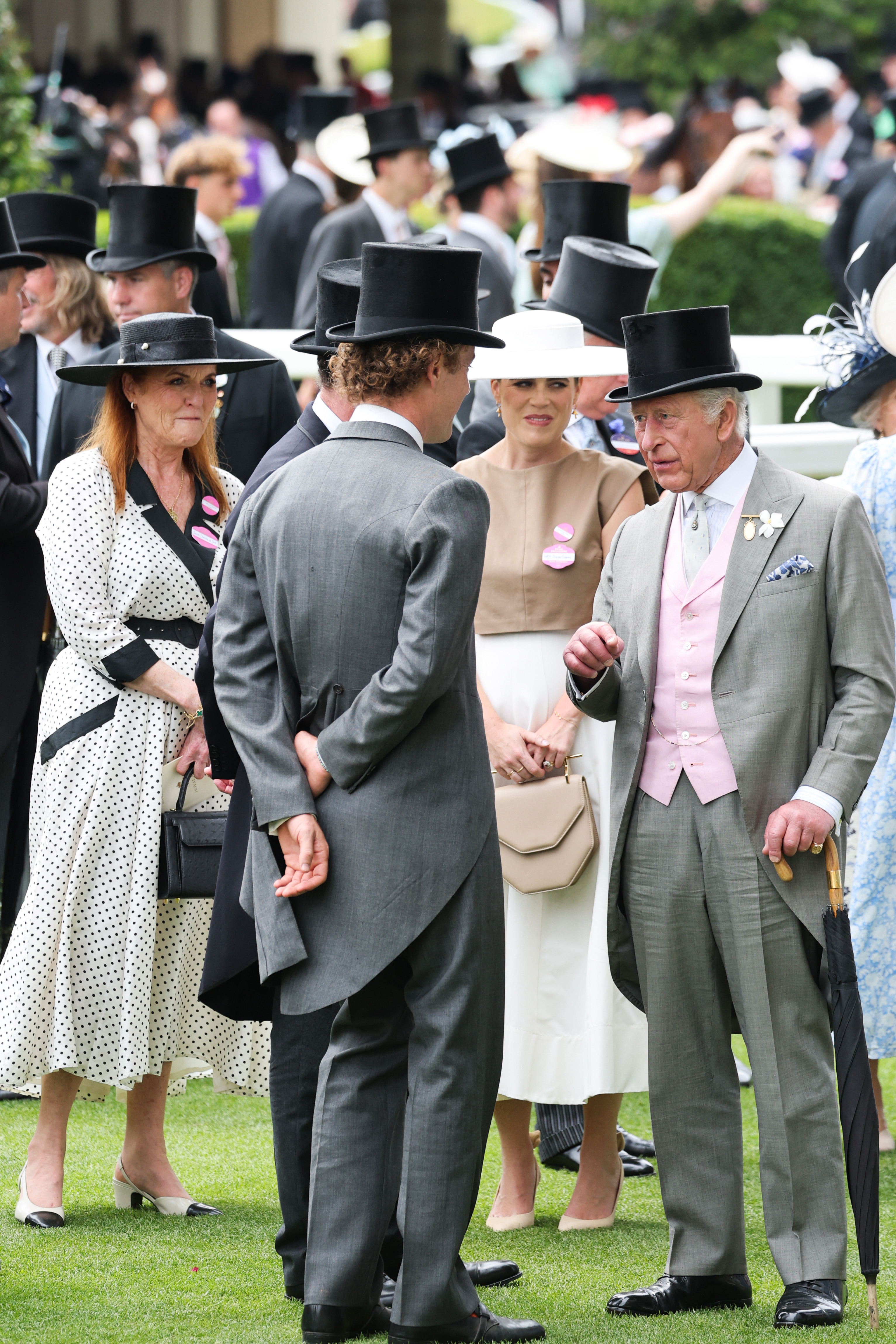 Sarah Ferguson wearing a white polka dot dress talking to Princess Eugenie and The King at Royal Ascot
