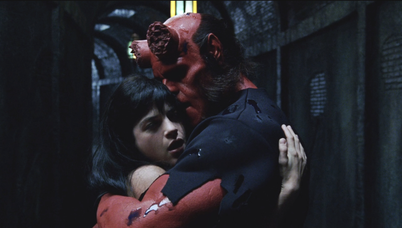 Selma Blair and Ron Perlman share an embrace in a tunnel in Hellboy.