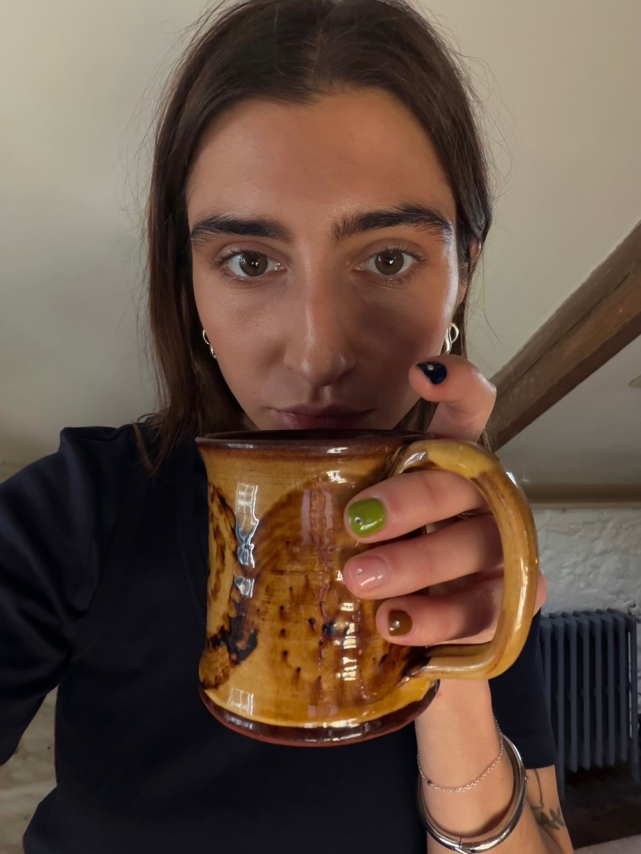 A woman holding a mug with a multicoloured manicure