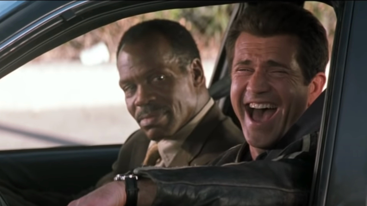 Danny Glover sonríe mientras Mel Gibson se ríe al volante en Arma Letal 4.