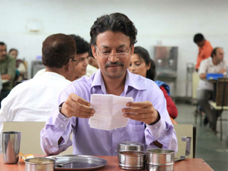 Irrfan Khan eating out of a home lunch at a cafeteria table in the lunchbox