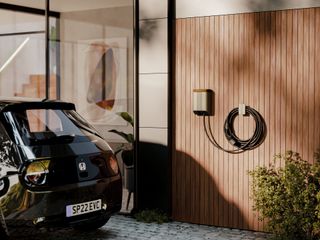 EV charger on wall of home beside car