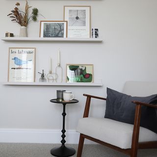 Living room storage with white floating shelves and armchair.