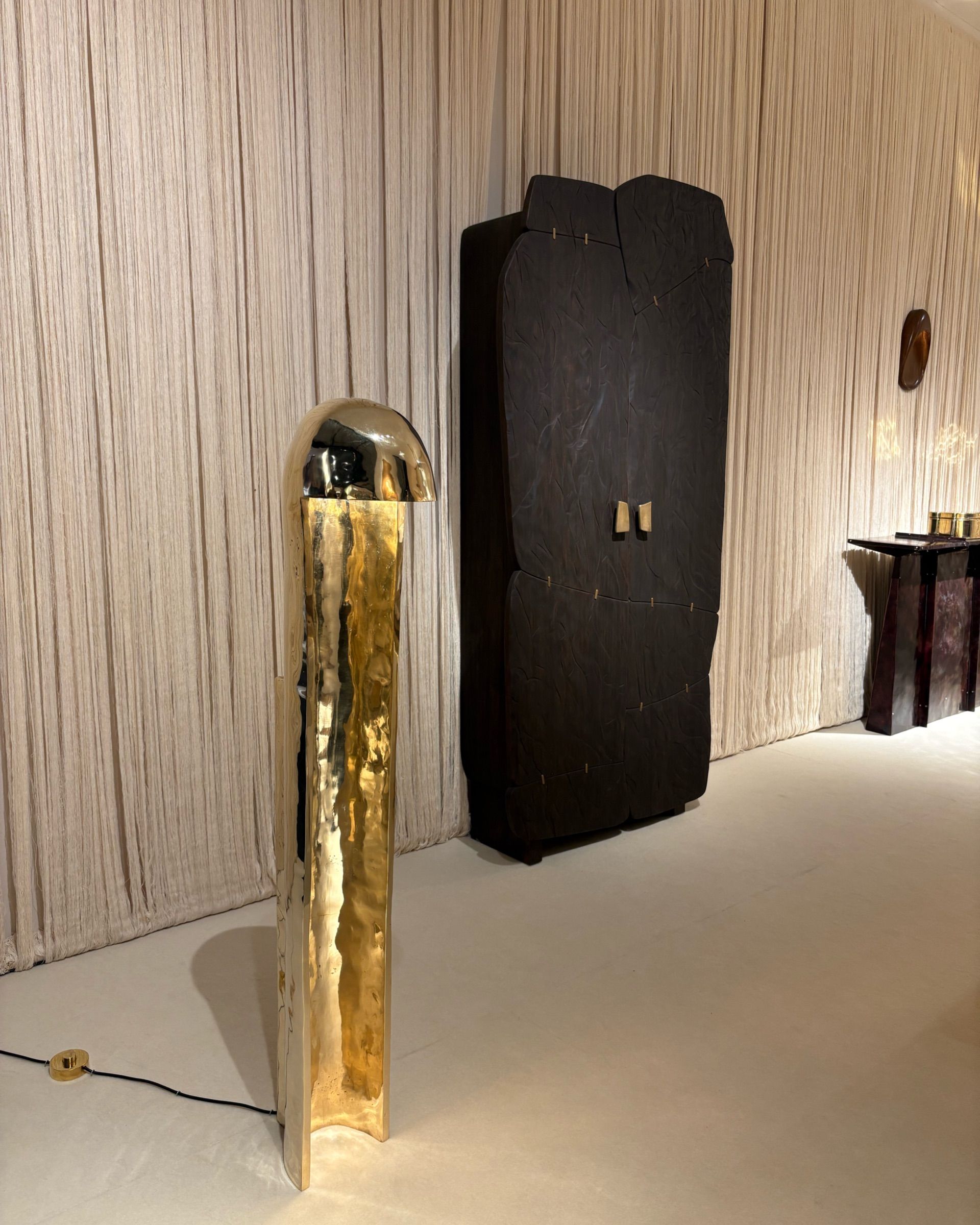 A series of contemporary furniture items with either a stitched-up or a tetris-looking structure sits in a warmly lit gallery space.