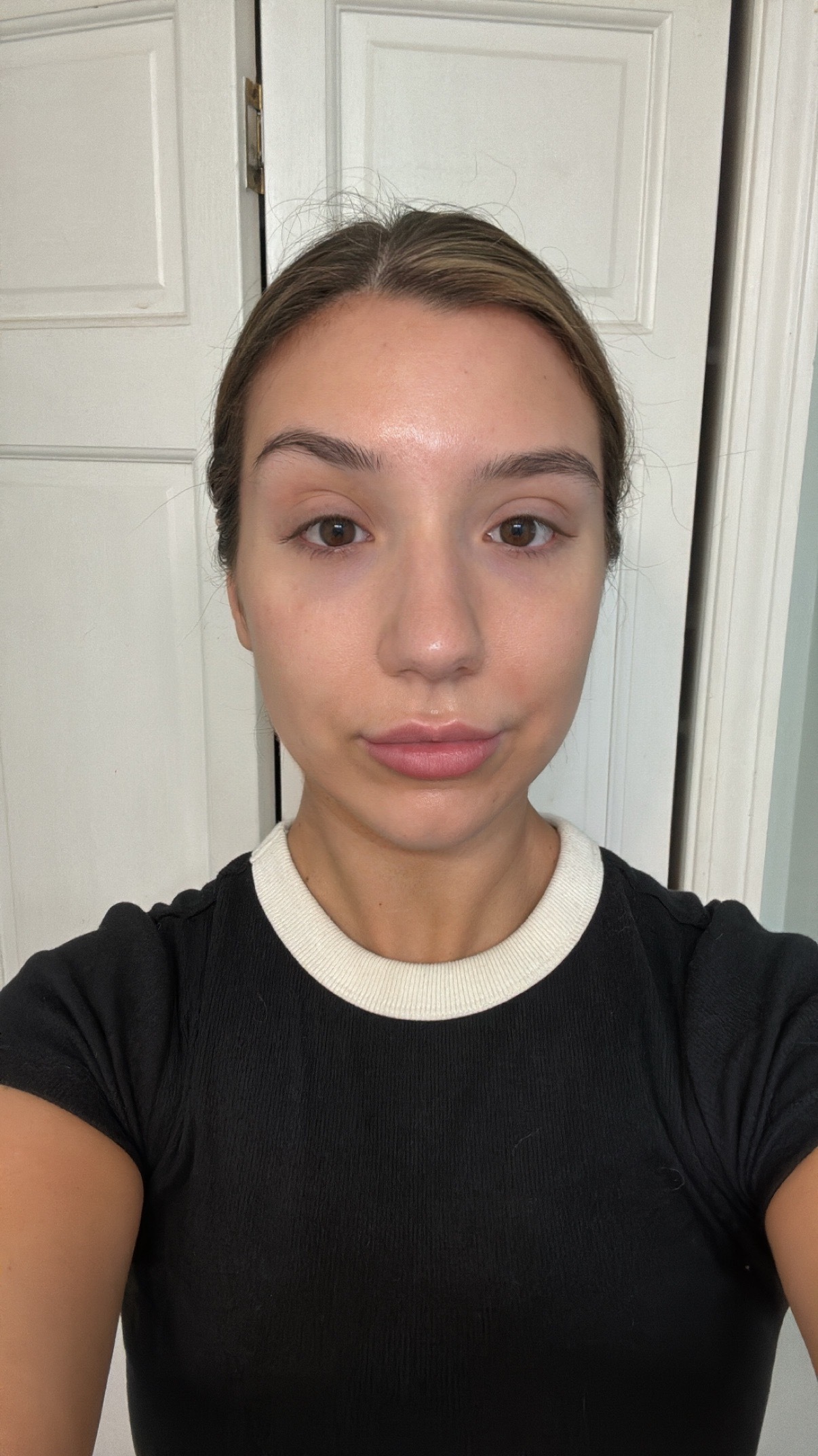 A girl with brown hair and a black shirt after applying spf.