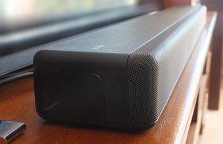 En svart Sony HT-G700 ligger på en TV-bänk. Sedd från sidan.