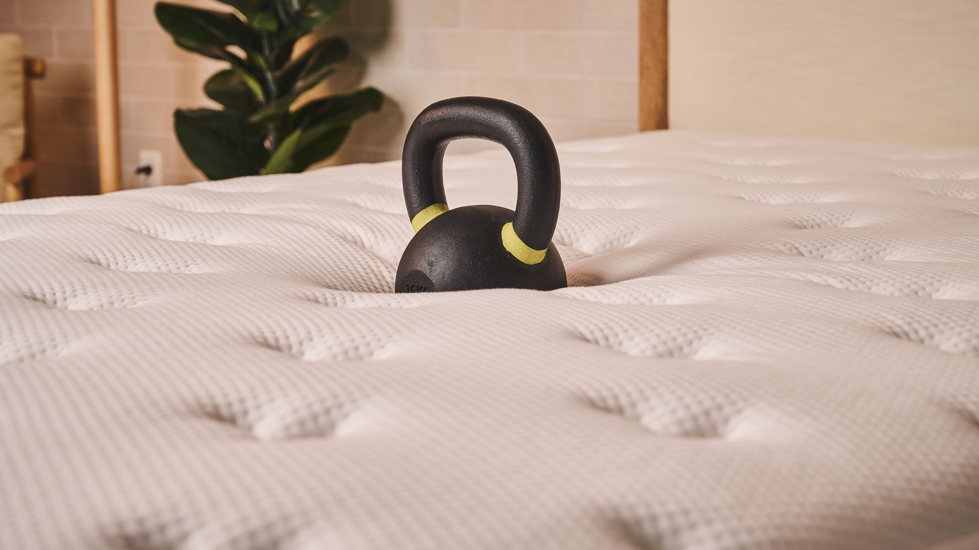 A kettlebell sinks into the surface of the Plank Firm Mattress, demonstrating the pressure relief