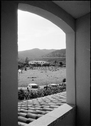 View through an archway of a vineyard and fields