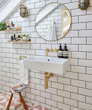 Loft bathroom with white metro tiles, industrial wall lights, and round wall mirror