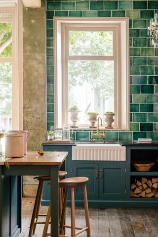 A Belfast sink or Butler's sink in a Devol kitchen with dark blue cabinets and green tiling wall