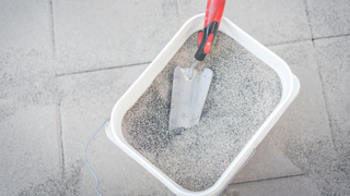 bucket of polymeric sand on paving slabs with a spade inside