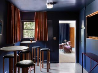 A blue room serving as the house bar, with a door leading to a space with Matt Helders' drums