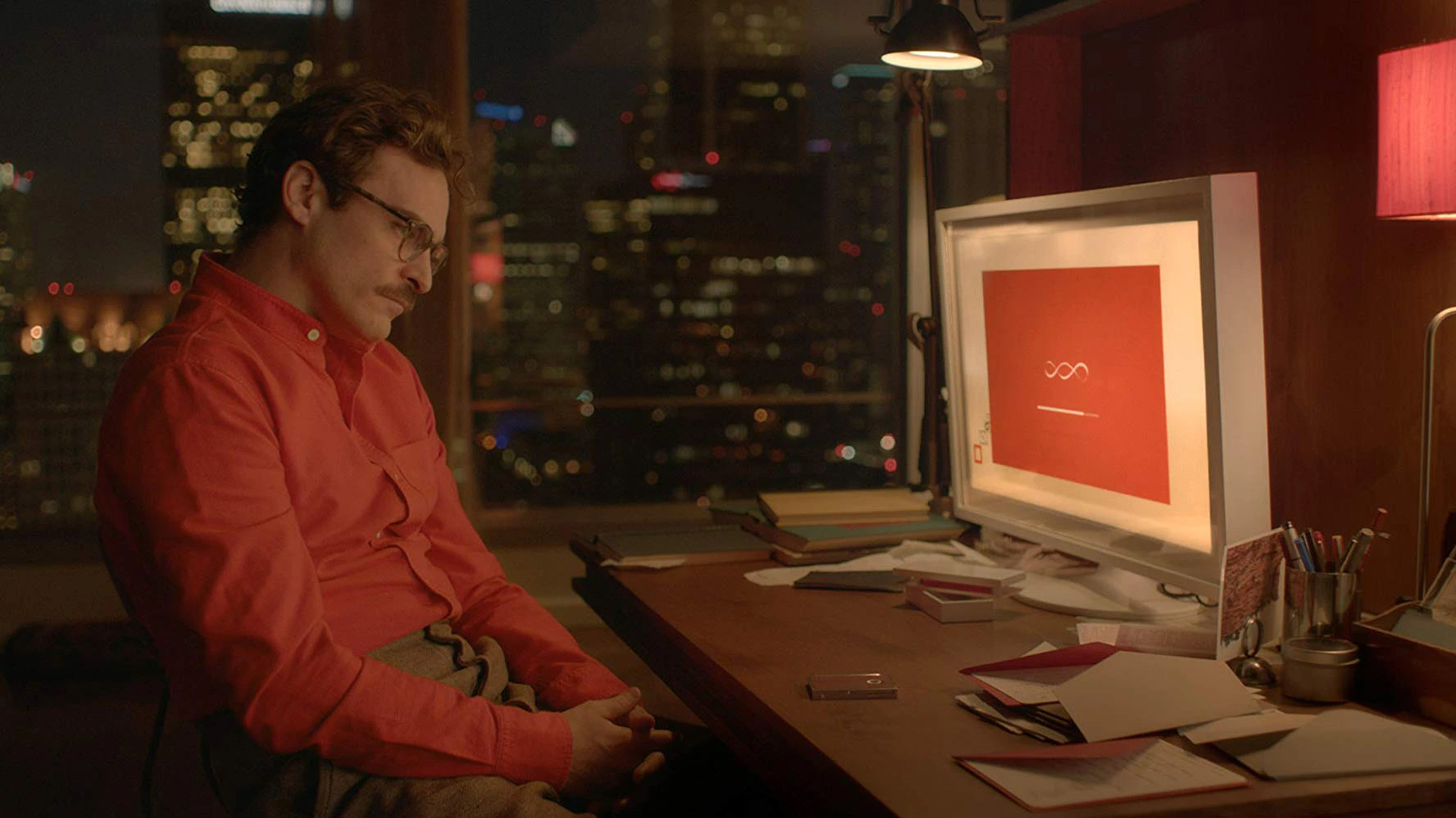 A still from the movie Her showing character Theodore Twombly (played by Joaquin Phoenix) staring at a computer