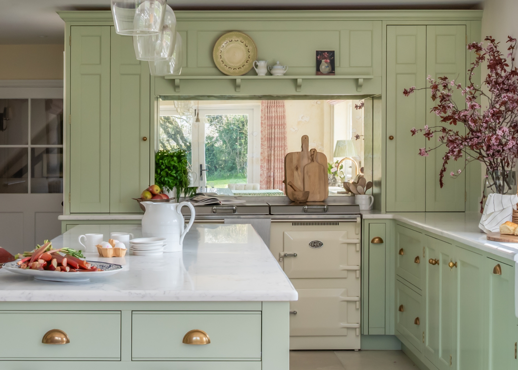 A sage green traditional kitchen with brass handles
