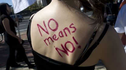 "NO means NO!" written in red lipstick on a woman's back