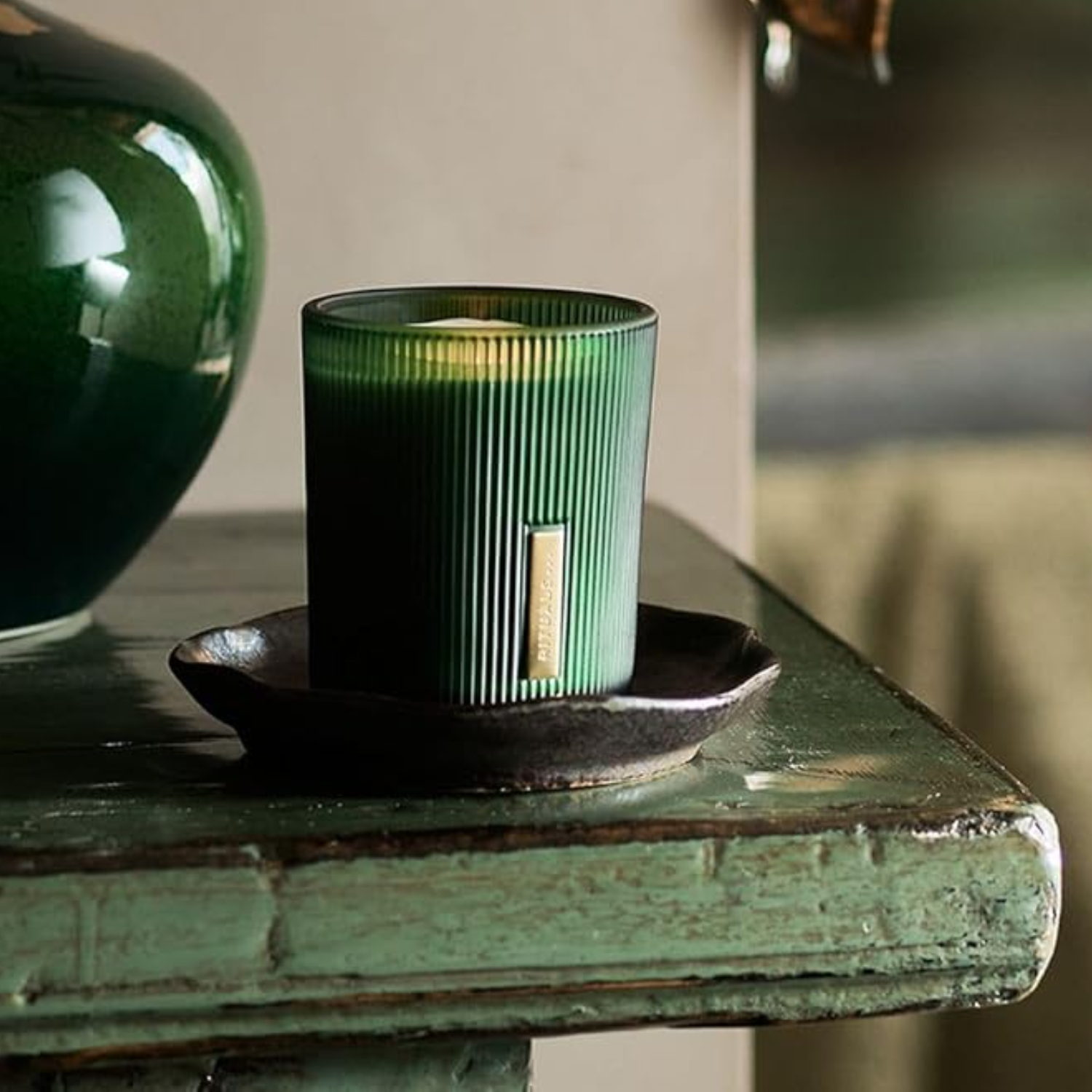A green ribbed glass candle on a ceramic plate