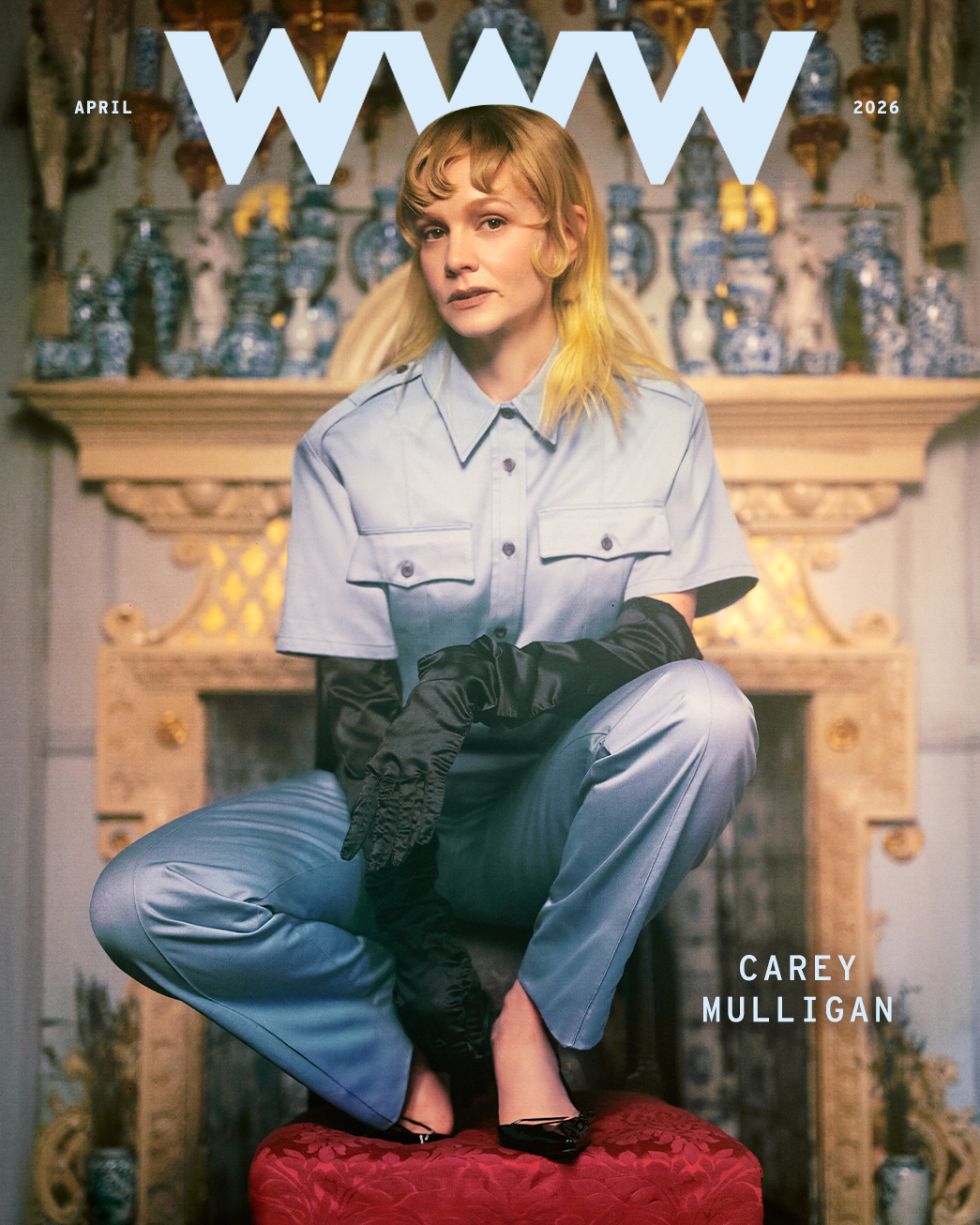 Carey Mulligan for Who What Wear's April cover story wearing a blue Prada jumpsuit with long black opera gloves squatting on a red cushion.