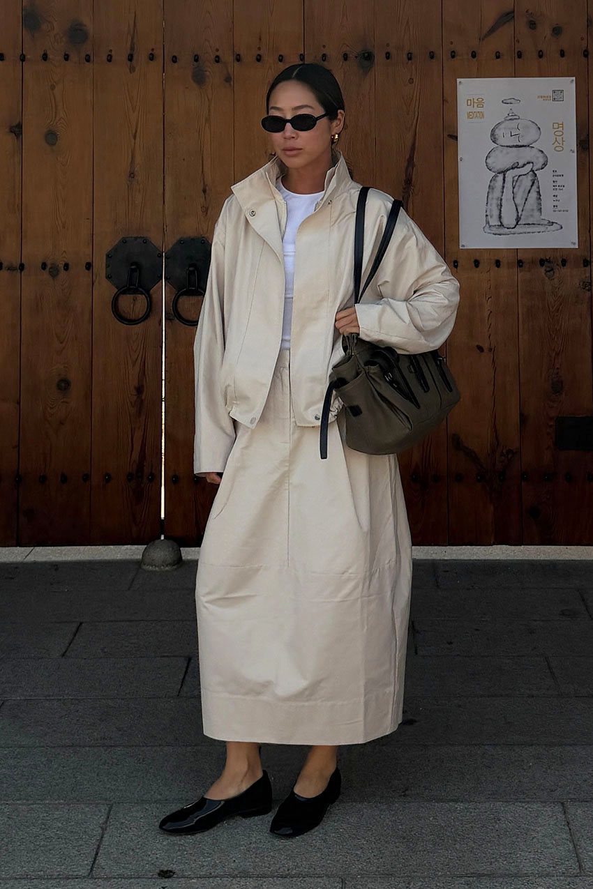A woman wearing a funnel neck jacket and matching skirt.