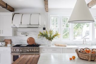 hamptons style kitchen close up with white cabinets, island and view through window