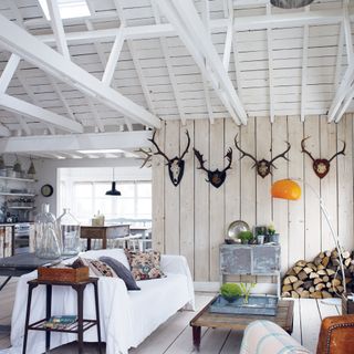 wood panelled open plan cabin living room and kitchen with vaulted ceiling and antlers on wall