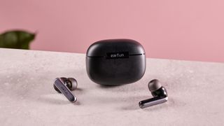 Earfun Air 2 NC and charging case on surface against pink background